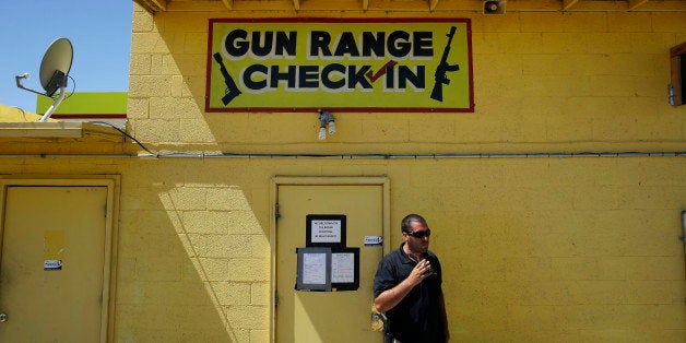 An employee smokes outside of an office for the Last Stop outdoor shooting range Wednesday, Aug. 27, 2014, in White Hills, Ar