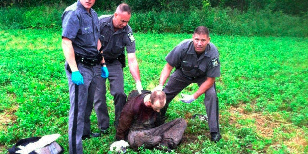 Police stand over David Sweat after he was shot and captured near the Canadian border Sunday, June 28, 2015, in Constable, N.Y. Sweat is the second of two convicted murderers who staged a brazen escape three weeks ago from a maximum-security prison in northern New York. His capture came two days after his escape partner, Richard Matt, was shot and killed by authorities. (AP Photo)