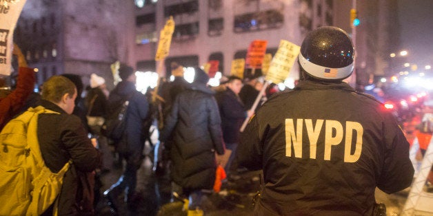 NEW YORK, NY - DECEMBER 23: An NYPD Officer on a motorbike keeps track of anti-NYPD protesters as they march through the Upper East Side of Manhattan on December 23, 2014 in New York City. Despite calls from New York City Mayor Bill de Blasio to curb protests until after the funerals of slain NYPD officers, demonstrators took to the streets to exercise their first amendment rights. (Photo by Michael Graae/Getty Images)