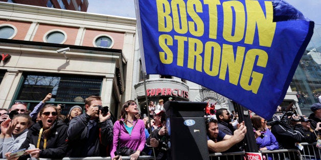 Race fans with a "Boston Strong" flag cheer for competitors near the finish line of the 118th Boston Marathon, Monday, April