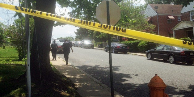 A Baltimore Police officer follows a man, who screamed "Let me in! I'm going in!" before crossing the yellow tape and walking