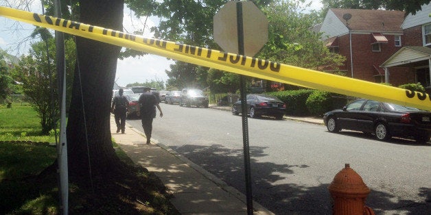 A Baltimore Police officer follows a man, who screamed "Let me in! I'm going in!" before crossing the yellow tape and walking into the crime scene on the 100 block of Upmanor Road, in Baltimore, where a young boy and a 31-year-old woman were shot and killed, Thursday, May 28, 2015. In the month since Freddie Gray died and the city erupted in civil unrest, Baltimore has seen its murder rate skyrocket. There have been 36 murders in May alone. (AP Photo/Juliet Linderman)