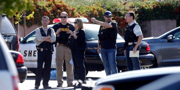 Law enforcement officers gather at the site where a Sacramento County Sheriff's deputy was shot by an assailant who then carjacked two vehicles prompting a manhunt in Sacramento, Calif., Friday, Oct. 24, 2014. The deputy was taken to a hospital but his condition is not immediately known.(AP Photo/Rich Pedroncelli)