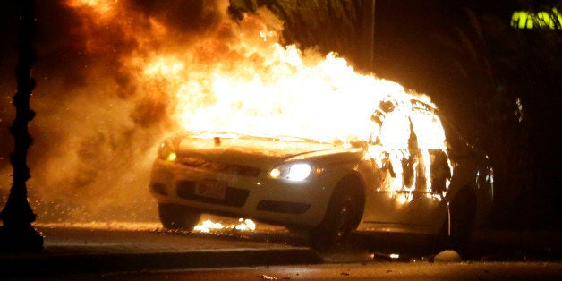 A police car is set on fire after a group of protesters vandalize the vehicle after the announcement of the grand jury decision Monday, Nov. 24, 2014, in Ferguson, Mo. A grand jury has decided not to indict Ferguson police officer Darren Wilson in the death of Michael Brown, the unarmed, black 18-year-old whose fatal shooting sparked sometimes violent protests. (AP Photo/Charlie Riedel)