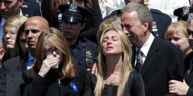 Police officer Brian Moore's mother Irene, left, sister Christine, center, and father Raymond react as his casket is placed in the hearse after his funeral mass, Friday, May 8, 2015, at the St. James Roman Catholic church in Seaford, N.Y. The 25-year-old died Monday, two days after he was shot in Queens. (AP Photo/Mary Altaffer)