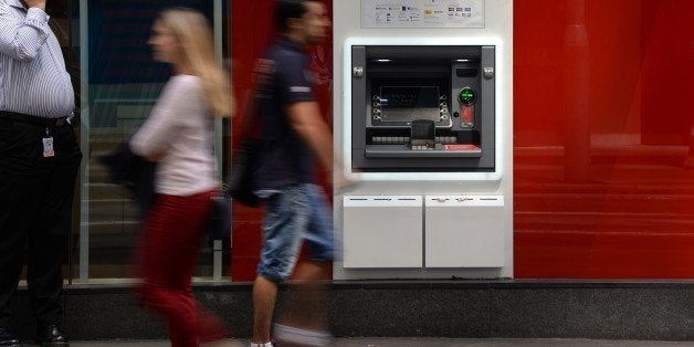 People walk past an ATM machine of Australian banking giant Westpac in the central business district of Sydney on November 3,