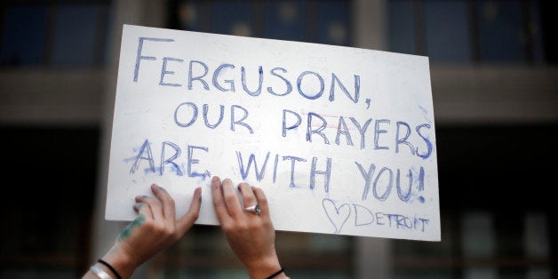 A participant holds a sign at a prayer vigil for Michael Brown outside the McNamara Federal Building in Detroit Monday, Aug. 25, 2014. Brown, a black 18-year-old who was unarmed, he was shot Aug. 9 in Ferguson, Mo., by Officer Darren Wilson, who is white. A grand jury is considering evidence in the case and a federal investigation is also underway. (AP Photo/Paul Sancya)