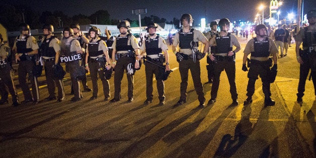 FERGUSON, MO - AUGUST 10: Police stand guard as demonstrators, marking the one-year anniversary of the shooting of Michael B