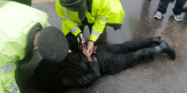 An unidentified man is taken into custody after performing an act of civil disobedience at the Ferguson, Mo., police station, Monday, Oct. 13, 2014, as hundreds continue to protest the fatal shooting of 18-year-old Michael Brown by police in August. In fact, tensions escalated last week when a white police officer shot and killed 18-year-old Vonderrit Myers Jr., who authorities say shot at police before he was killed. (AP Photo/Charles Rex Arbogast)