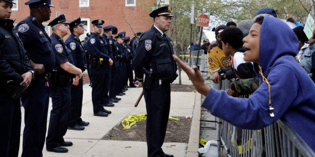 Members of the Baltimore Police Department stand guard outside the department's Western District police station during a prot