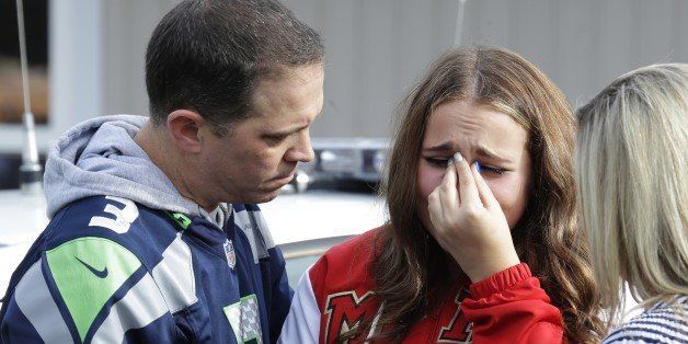 ADDS NAMES- Dan Simenson, left, comforts his daughter Hailee, center, 16, at a church, Friday, Oct. 24, 2014, where students were taken to be reunited with parents following a shooting at Marysville Pilchuck High School in Marysville, Wash. (AP Photo/Ted S. Warren)