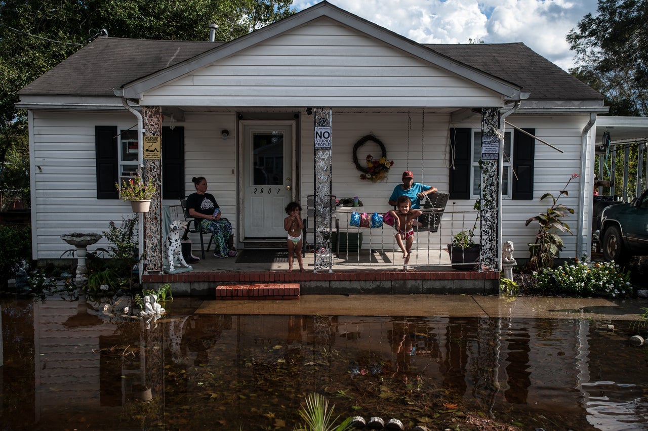 Gloria Freeman and her children, Bella and Cullen Jr., sit on their porch with Johnny Oxdine as floodwaters fill their yard in Lumberton.