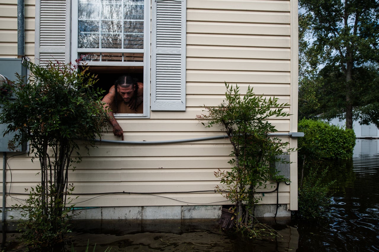 Floodwaters fill William Colville's yard as he points to the level the water reached at its peak in Lumberton.