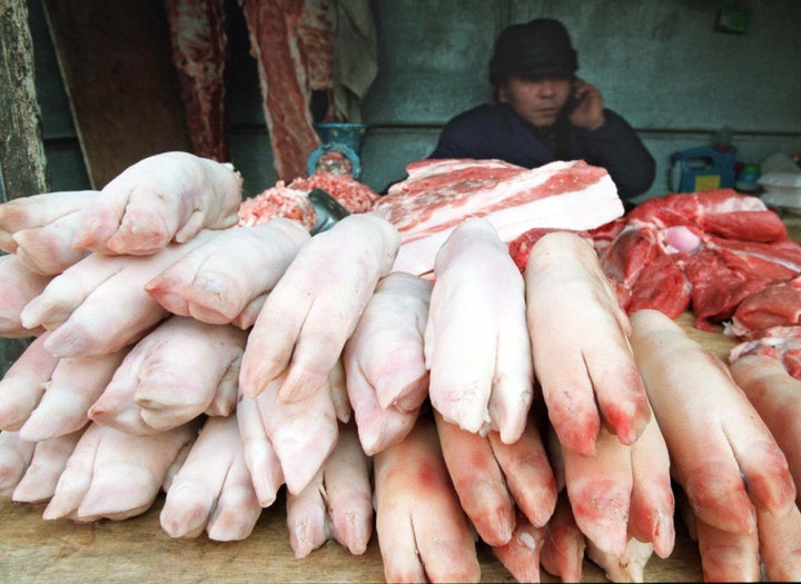 A meat vendor sits behind a pile of pigs feet for sale in central Beijing.