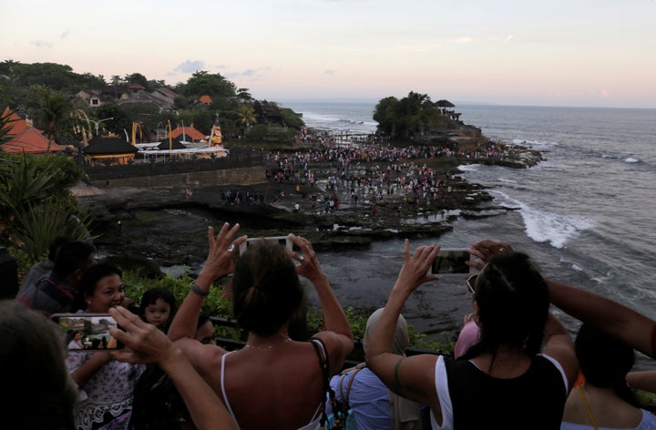 Tourists take pictures of the Hindu temple Tanah Lot (R) in Tabanan, on the resort island of Bali, Indonesia May 6, 2018.