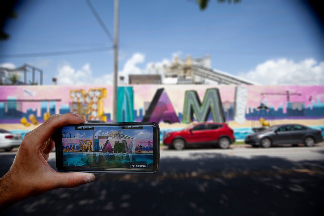 A viewer uses their smartphone to view ‘What Future Do You Choose for Miami?’, an augmented reality mural in the city.