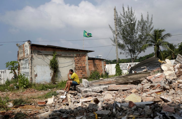 A man sits atop the rubble of his home in Vila Autodromo, a Rio de Janeiro neighborhood that was destroyed to make way for th