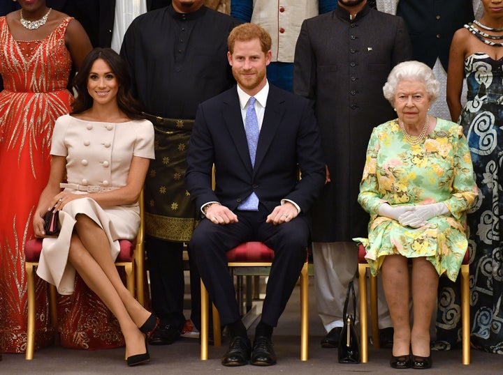 Queen Elizabeth, Prince Harry and Meghan, the Duchess of Sussex pose for a picture with some of Queen's Young Leaders at a Buckingham Palace reception on June 26. 