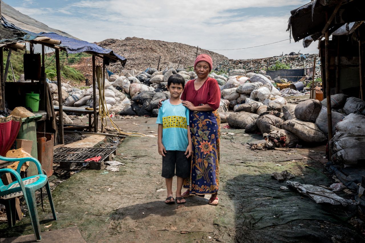 Reza, left, with Mak Muji, the midwife who helped deliver him, in front of his family's shack.