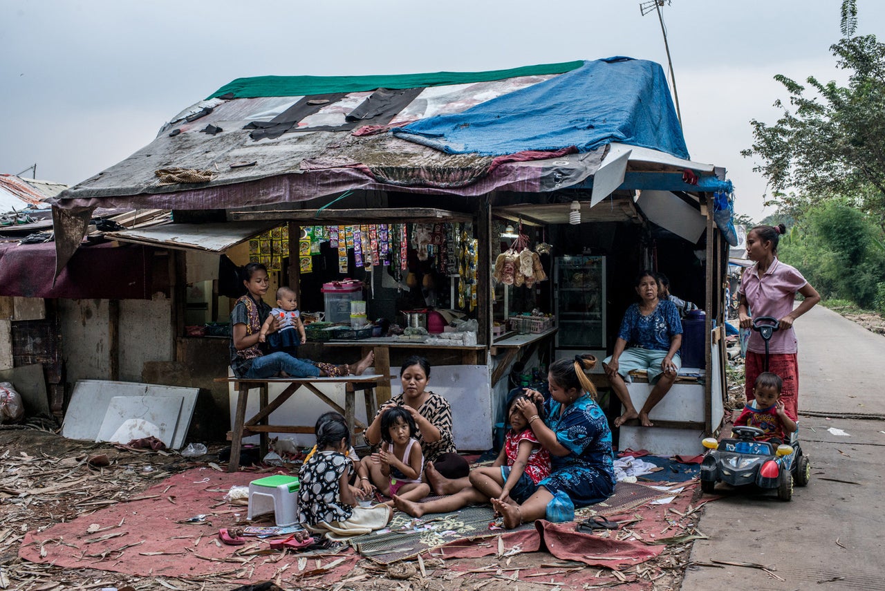 In a village at the edge of the landfill, a kiosk selling food and consumer goods becomes a gathering place for women and children in the evening.