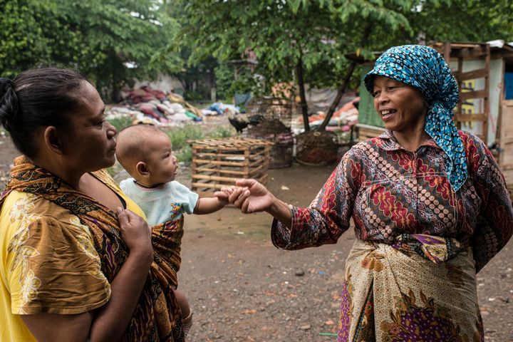 Mak Muji, on a stroll through her village, greets a mother holding a baby she helped deliver.