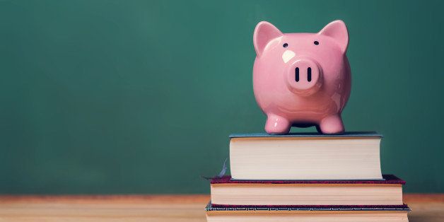 Pink Piggy bank on top of books with chalkboard in the background as concept image of the costs of education