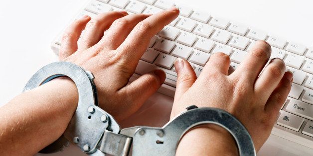 A young woman's hands are locked into handcuffs as she 'slaves away' on a white computer keyboard, against a white background. Could symbolize being stuck in a demanding or boring job or an inability to leave her computer due to a passion for internet browsing! 