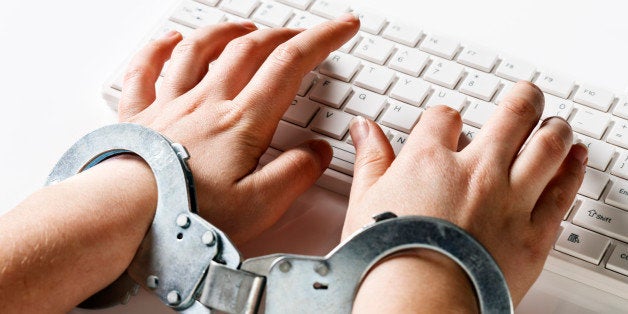 A young woman's hands are locked into handcuffs as she 'slaves away' on a white computer keyboard, against a white background. Could symbolize being stuck in a demanding or boring job or an inability to leave her computer due to a passion for internet browsing!