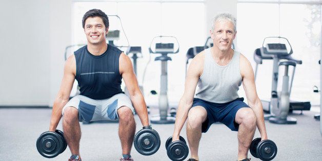 Men doing squats with dumbbells in gymnasium