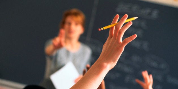 Teacher pointing to raised hands in classroom