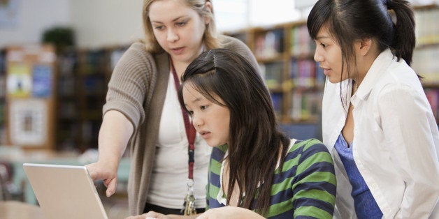 Librarian helping students with research in school library