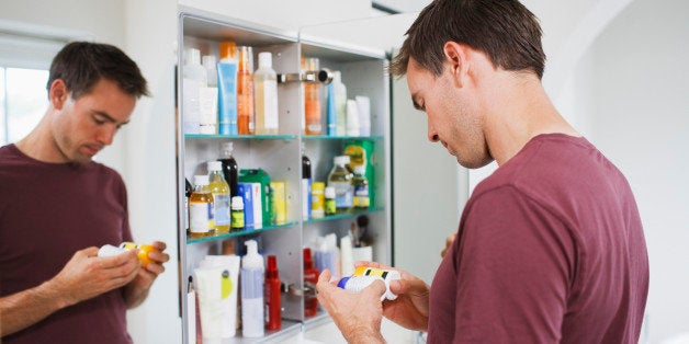 Man looking at bottles from medicine cabinet