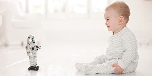 Baby on floor looking at toy robot