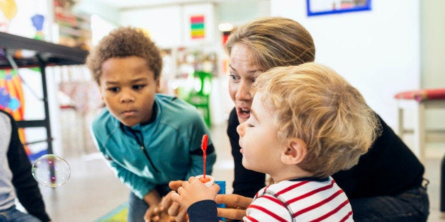 Teacher and children playing with bubbles in kindergarten