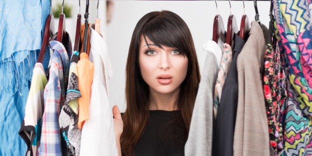 Portrait of young confused woman in front of a wardrobe full of clothes. Nothing to wear concept