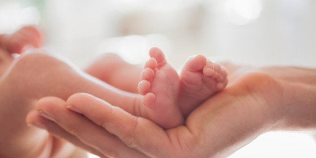 Mother cradling newborn baby's feet