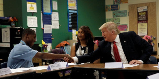 Republican presidential nominee Donald Trump shakes hands with 12 year old student Egunjobi Songofunmi during a campaign visi