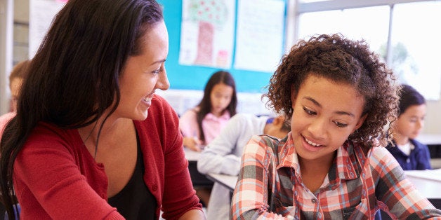 Teacher working with elementary school girl at her desk