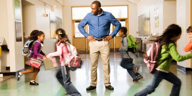 Blurred motion shot of students running past teacher