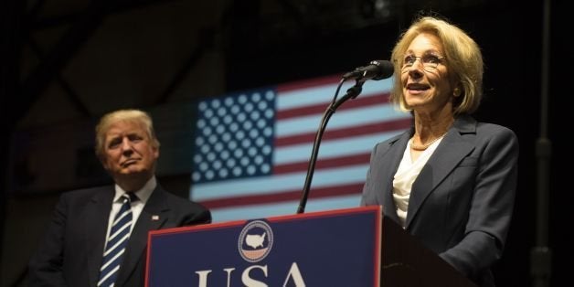 US President-elect Donald Trump listens as Betsy DeVos, his pick for education secretary, speaks during the USA Thank You Tour December 9, 2016 in Grand Rapids, Michigan. / AFP / DON EMMERT (Photo credit should read DON EMMERT/AFP/Getty Images)