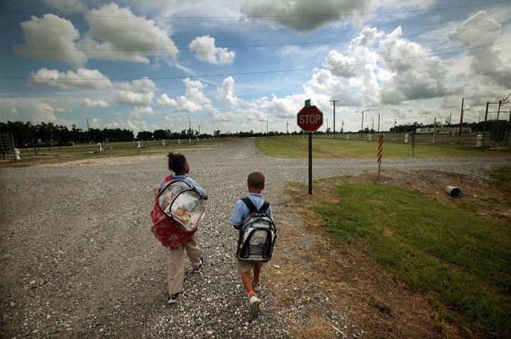 PORT SULPHUR, LA - MAY 14: Herschel Barthelemy and sister Jalinh Vasquez walk home in the FEMA Diamond trailer park after getting dropped off by the school bus May 14, 2009 in Port Sulphur, Louisiana. Seven children and four adults from the family are still living in a FEMA trailer after their home was destroyed by Hurricane Katrina. The trailer park used to house hundreds of families but just a few still remain. They are still awaiting money from the federal Road Home program to purchase a new home. Approximately 2,000 families in the New Orleans metropolitan area still live in FEMA trailers nearly four years after Hurricane Katrina. Eighty percent of those still in trailers are homeowners who are unable to return to their storm damaged houses. May 1 marked the end of the Temporary Housing Program for Katrina victims as those still living in the trailers have been given a May 30 deadline to move out or face possible legal action. (Photo by Mario Tama/Getty Images)