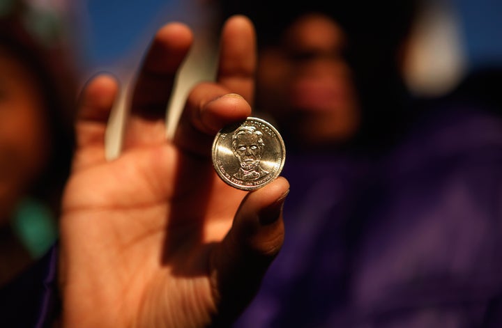 WASHINGTON - NOVEMBER 19: A student from the William E. Doar Jr. Public Charter School for the Performing Arts holds up the new presidential one-dollar coin with the image of Abraham Lincoln she was given during an introduction event at President Lincoln's Cottage at the Soldiers' Home November 19, 2010 in Washington, DC. The United States Mint introduced the coin on the 147th anniversary of Lincoln's Gettysburg Address. (Photo by Chip Somodevilla/Getty Images)