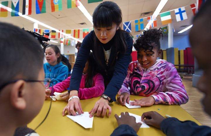 Japanese School Teacher Haruna Konno (C) from Fukuoka Elementrary School, helps US school kids make origamis after the learning part of the school class experience where the children heard about the March 11, 2011, Japan killer earthquake and tsunami where she escaped with her life, January 5, 2012 in Washington, DC. These Washington, DC inner-city, low-income immigrant children from around the world were introduced to stories of the disaster as well as learning how to make origamis and use chop sticks as part of a Goodwill Embassy Adoption Program. AFP Photo/Paul J. Richards (Photo credit should read PAUL J. RICHARDS/AFP/Getty Images)