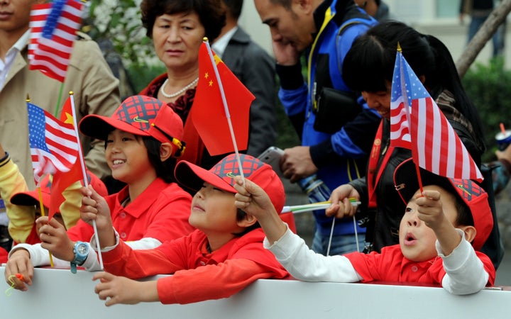 TO GO WITH US-vote-China,FOCUS by Sebastien Blanc Chinese children wave their national flag together with the US flags as they attend the one-day golf challenge between Tiger Woods of the US and Rory McIlroy of Northern Ireland in Zhengzhou, in central China's Henan province on October 29, 2012. The world's two biggest economies choose their next leaders in early November, an accident of timing that puts China's opaque communist state and America's riotous democracy in stark contrast. AFP PHOTO/GOH CHAI HIN (Photo credit should read GOH CHAI HIN/AFP/Getty Images)