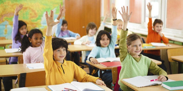 Elementary school students with their hands raised to ask a questions.