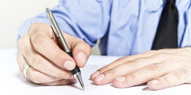 Businessman signing contract. Business man in blue shirt is signing agreement document.