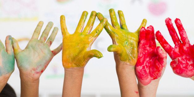 kids hands covered with paint in classroom
