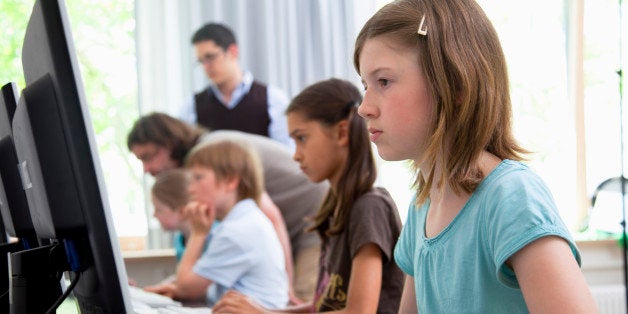 Male teachers helping pupils in computer room, Hamburg, Germany