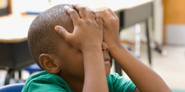 Frustrated boy rubbing eyes in classroom