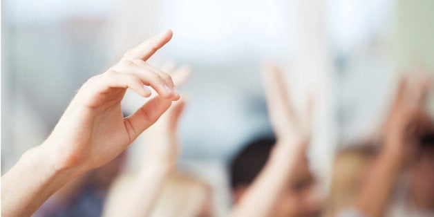 A group of students raising their hands in class.